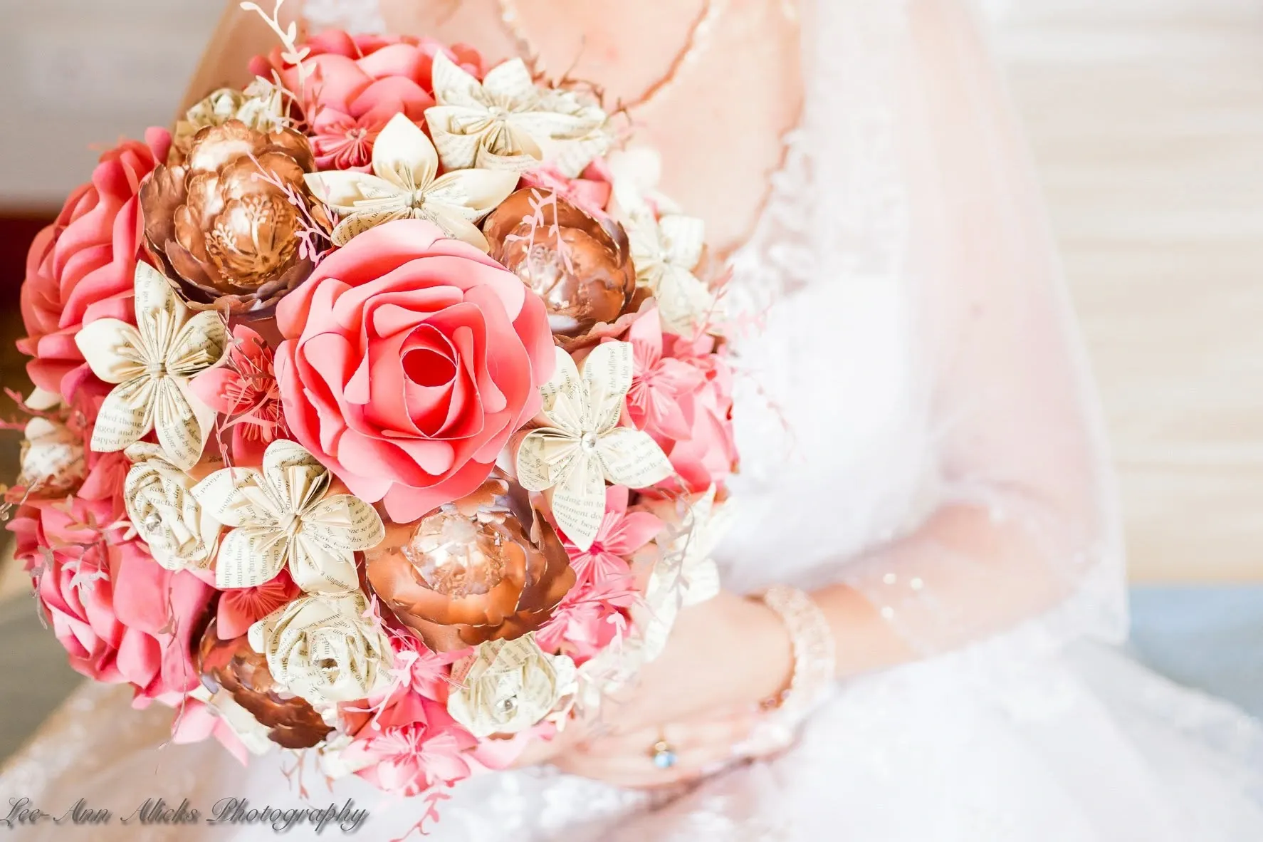 Close-up of a handmade paper bridal bouquet of coral roses, copper blooms and flowers folded from book pages.