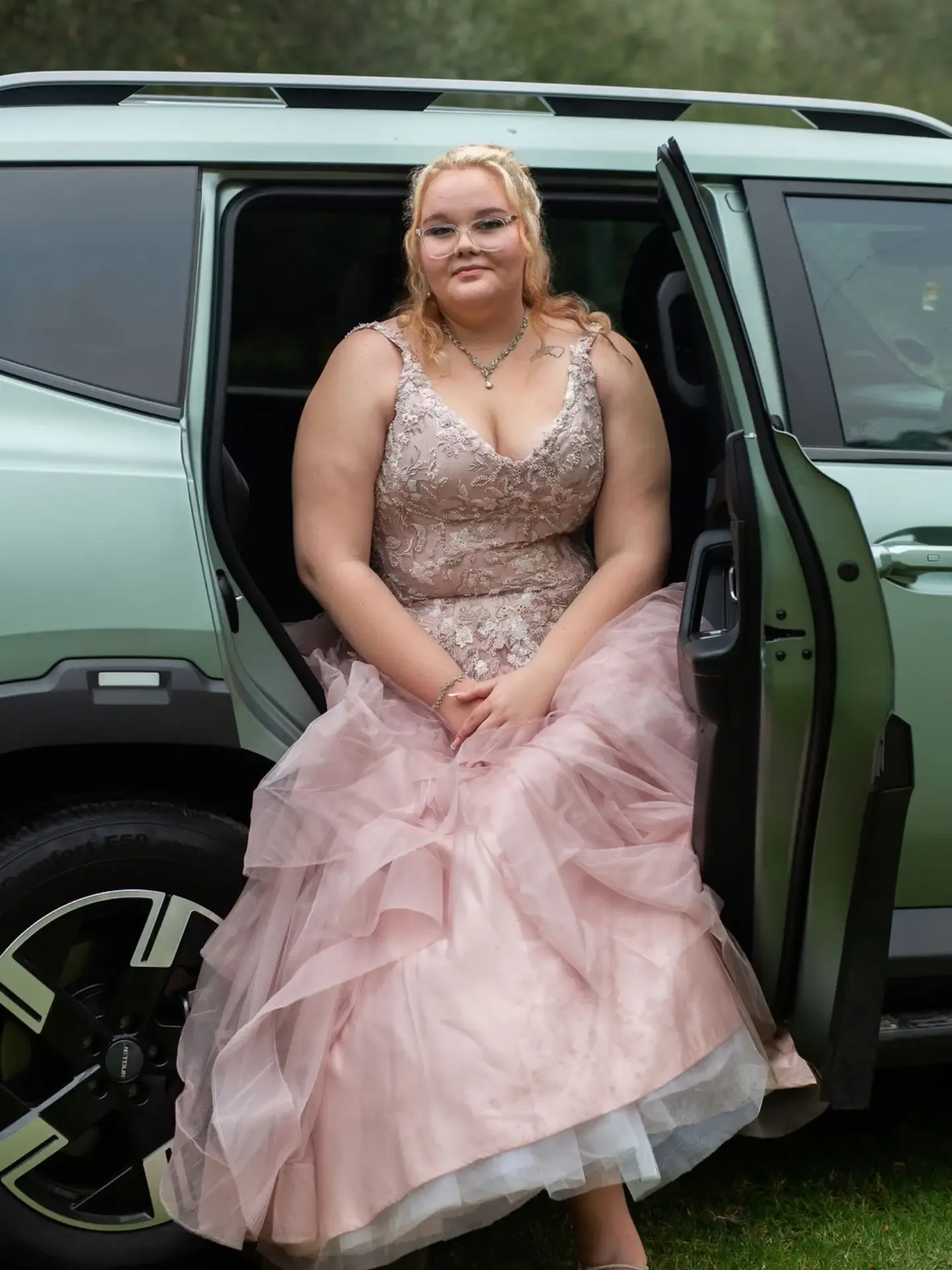 Matriculant in a ball gown seated in the open door of the car before leaving for the dance.