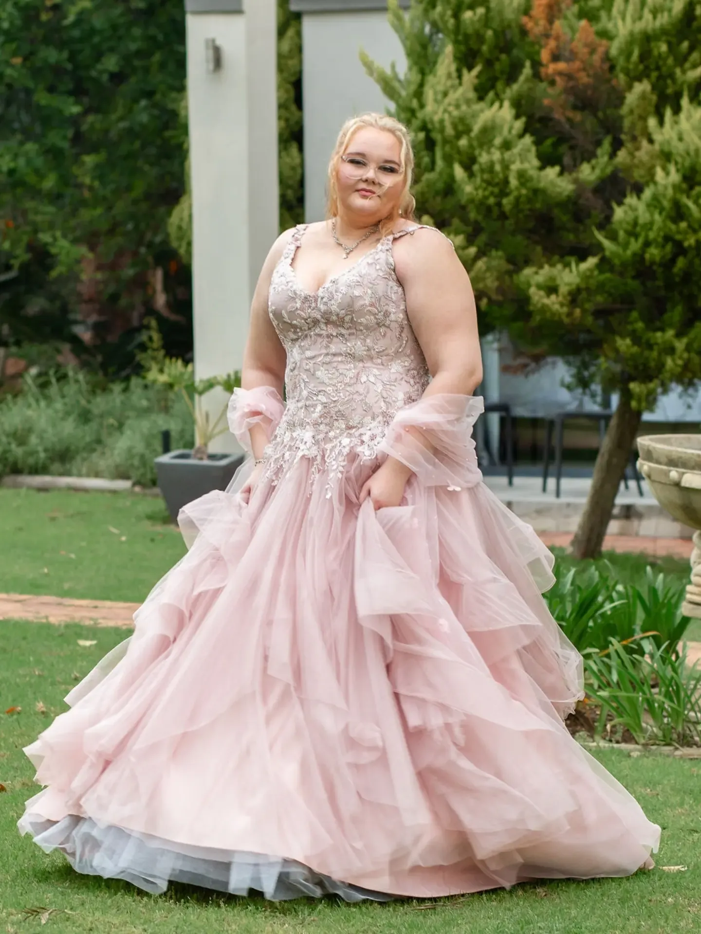 Full-length matric dance portrait in a layered pink ball gown with a sheer wrap.