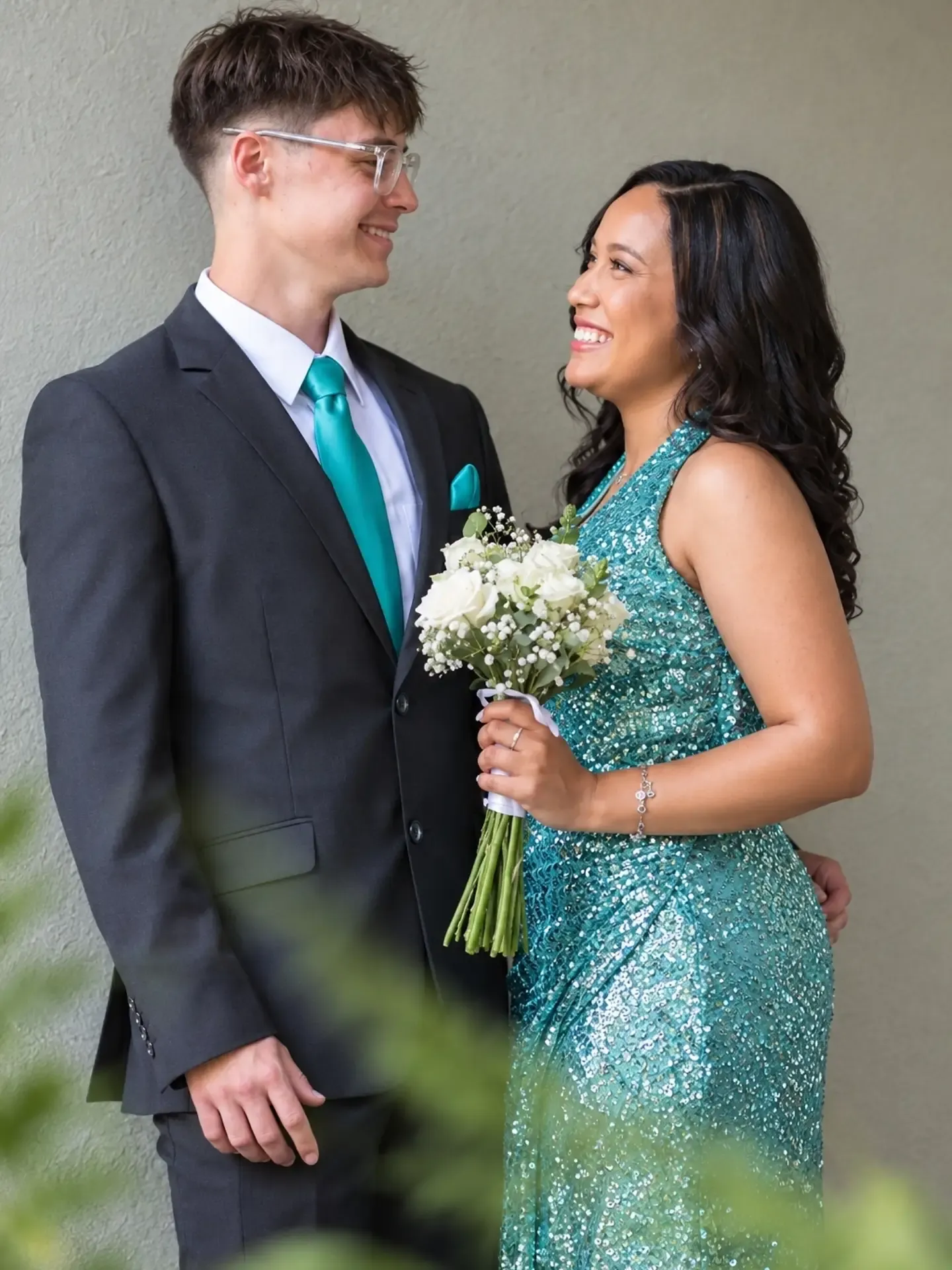 Close portrait of a matric farewell couple, she holds a white rose bouquet.
